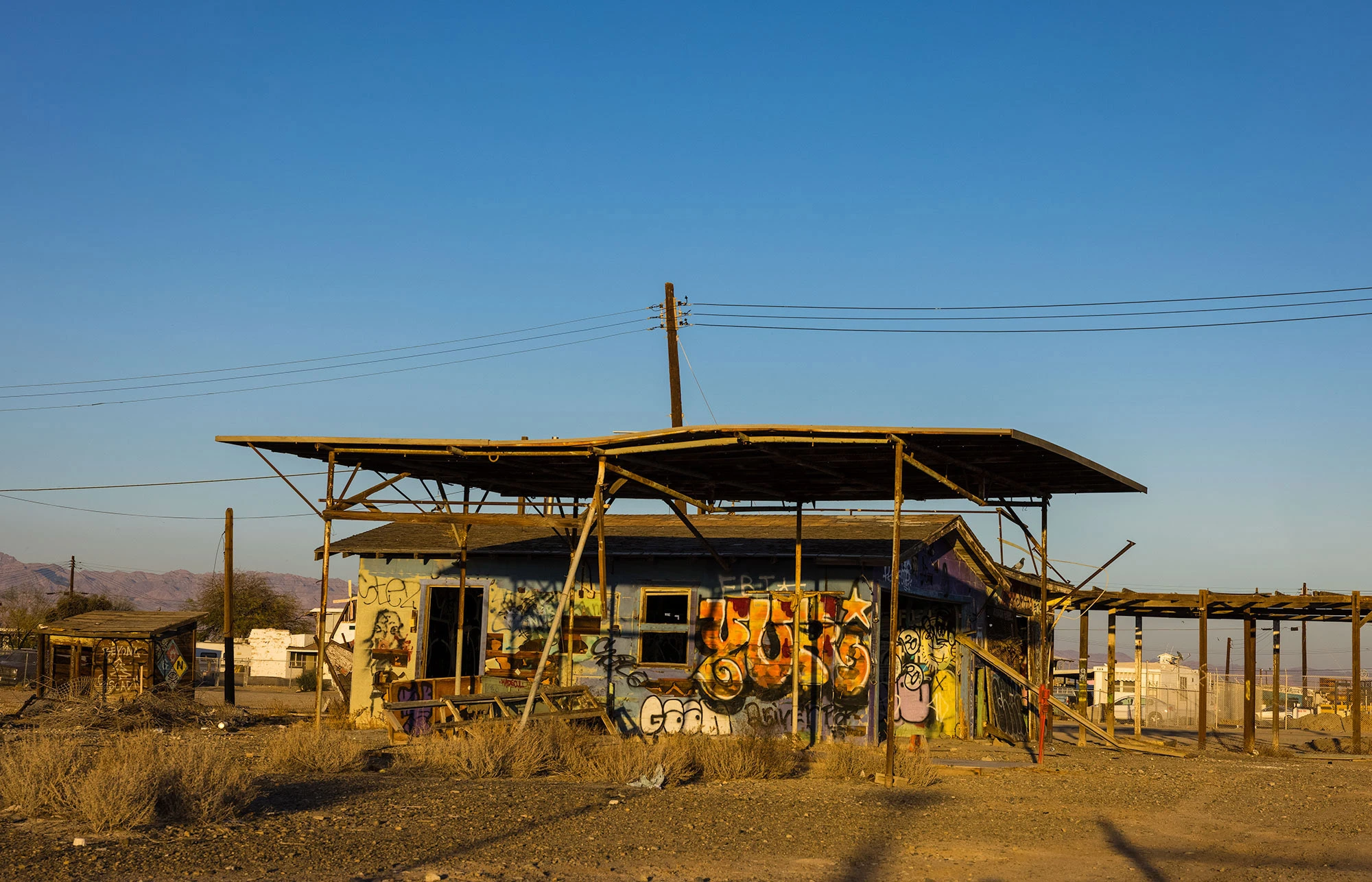 Abandoned house in Bombay Beach on California's Salton Sea, its roof caved and walls crumbling under the desert sun, a haunting relic of the town's collapse after flooding and rising salinity drove residents away.