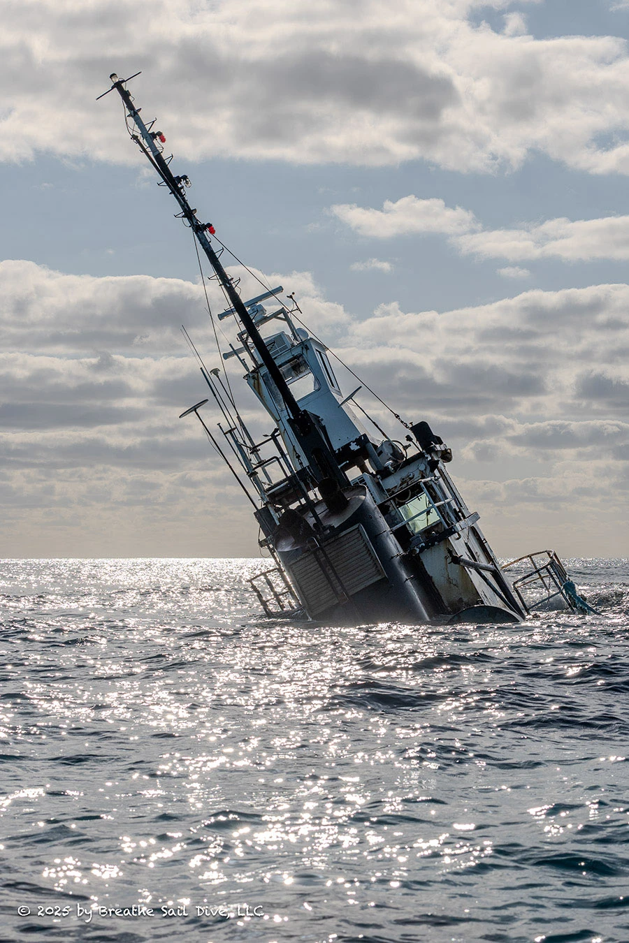A tugboat leans at a steep angle in the ocean near Fowl Cays National Park.