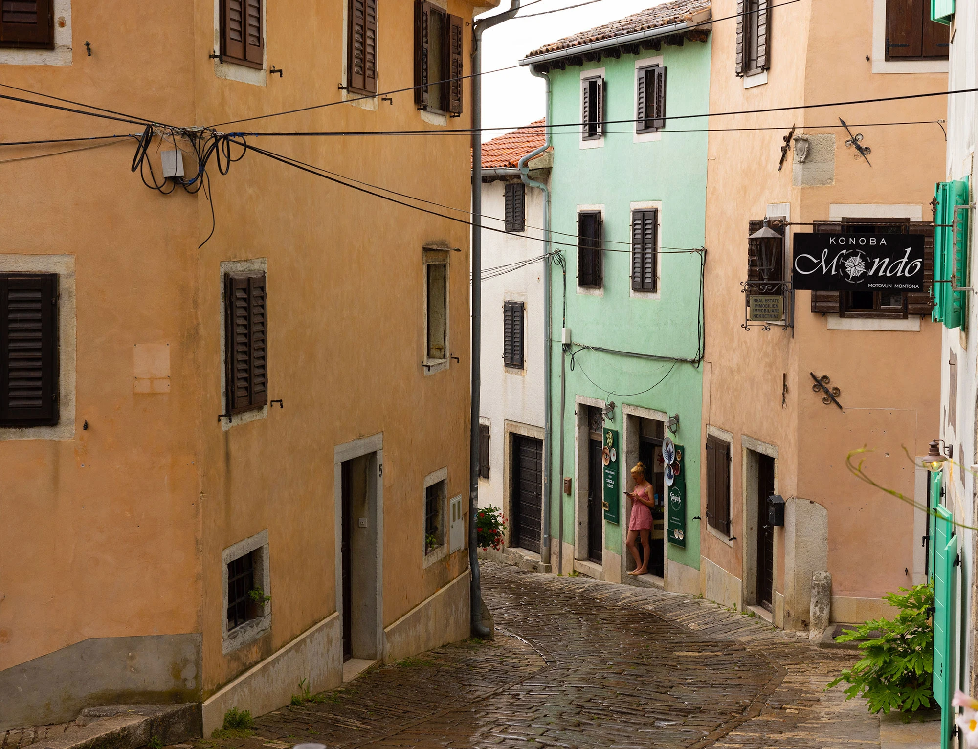 A shopkeeper in a pink dress reads her phone during a thunderstorm in Motovun, Croatia.