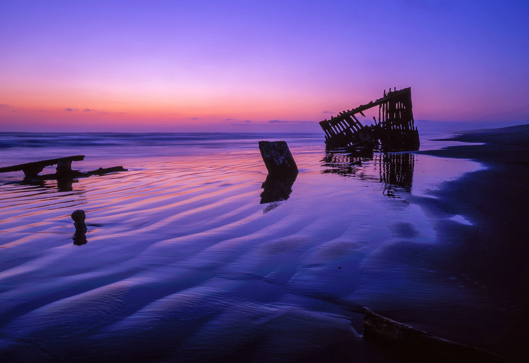 Peter Iredale shipwreck on the Oregon Coast with rusted steel bones rising from the sand at low tide