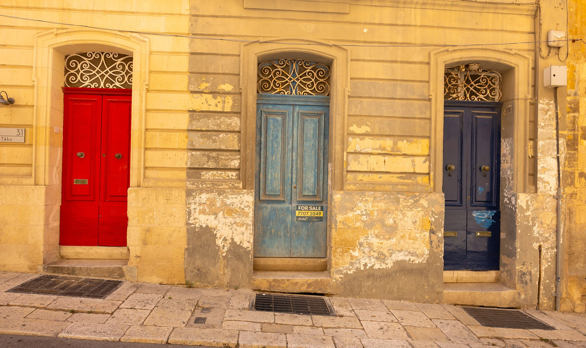 Colorful Maltese doors in a sunlit alley of Valletta, Malta